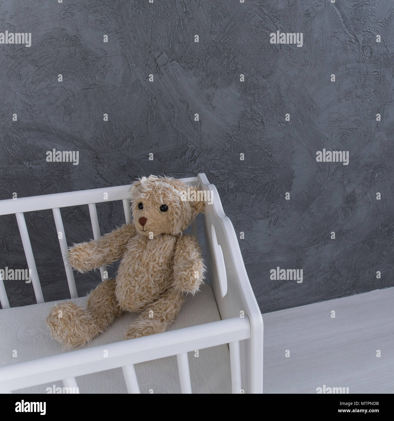 Shot of a teddy bear sitting in a crib in a grey nursery room Stock Photo Alamy