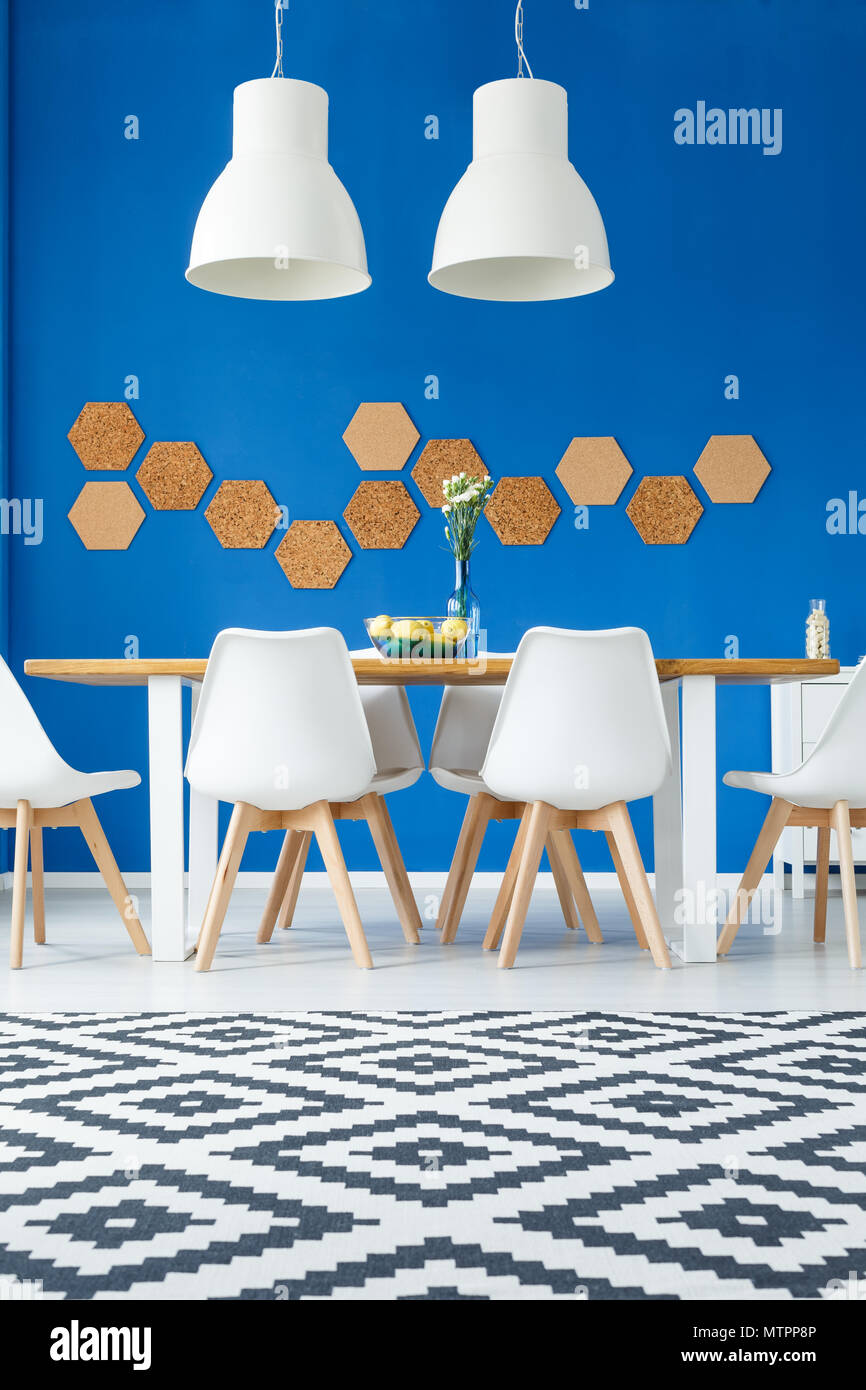 DIY cork on blue wall in modern natural dining room with wooden communal table, white