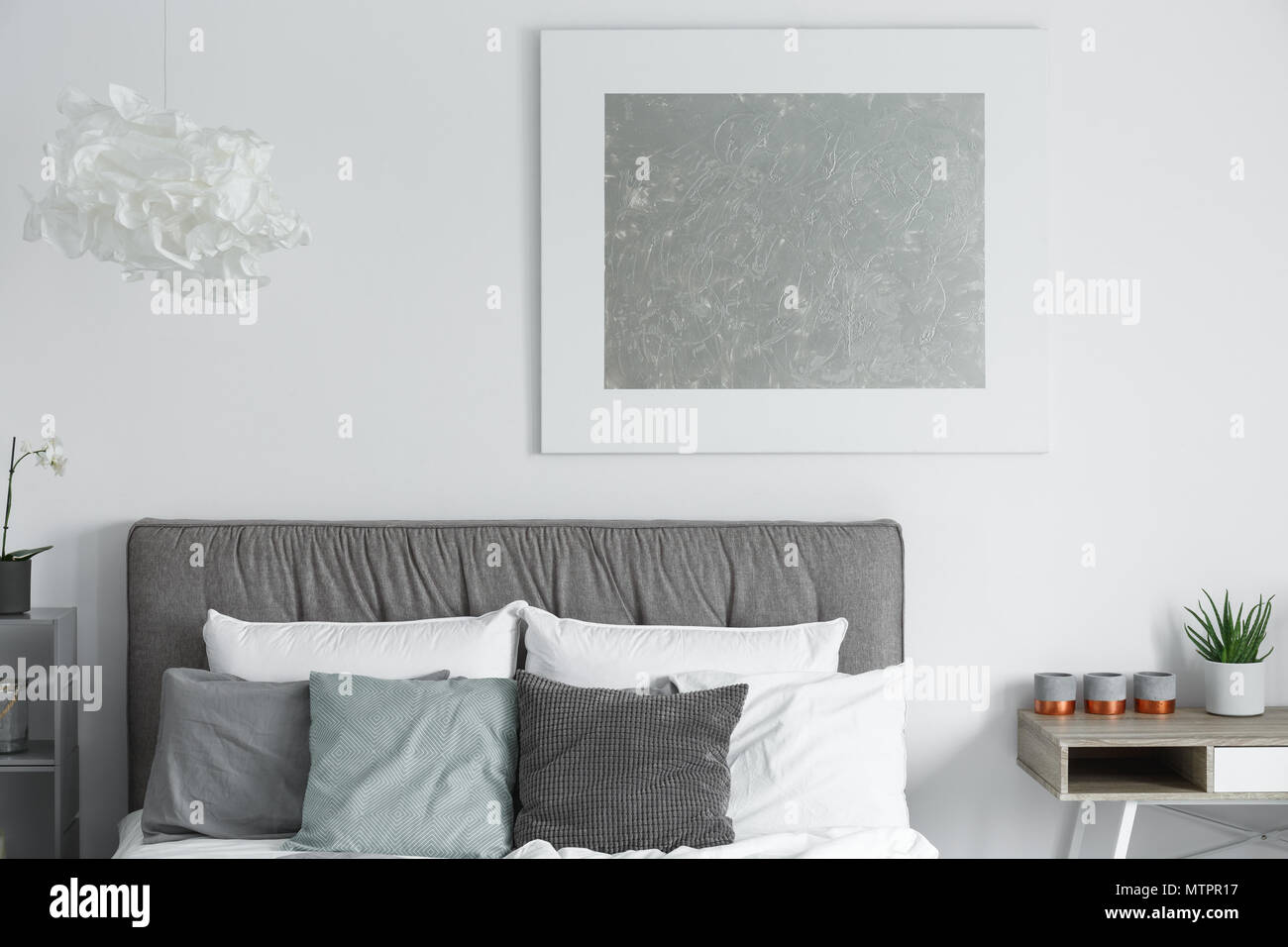 Big modern poster hanging on white wall in stylish bedroom Stock Photo