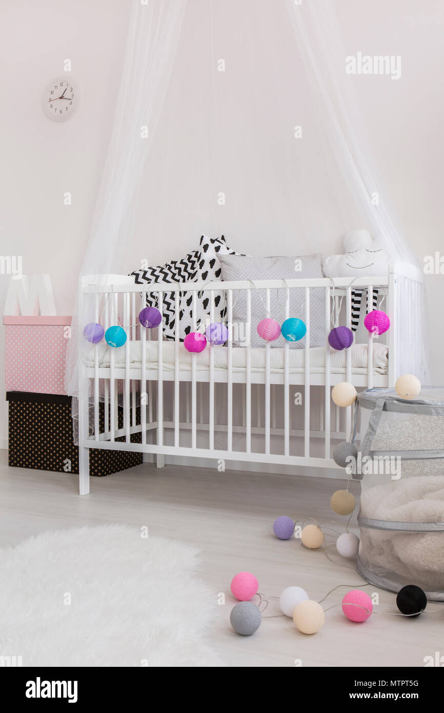 Close-up of white baby's cradle with canopy decorated with colorful bulbs Stock Photo