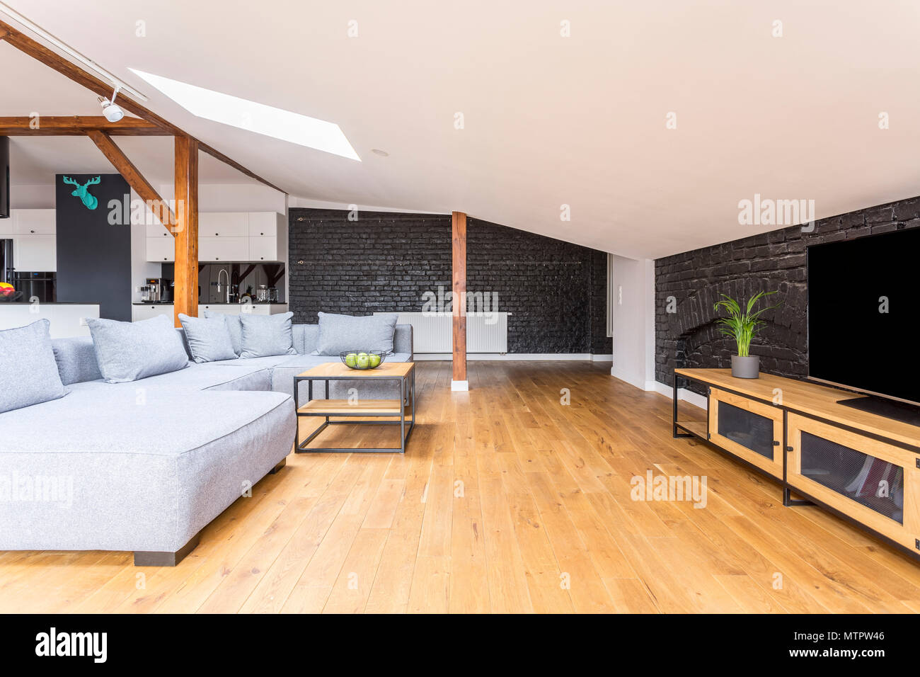 Television on long wooden cupboard in living room with grey couch set