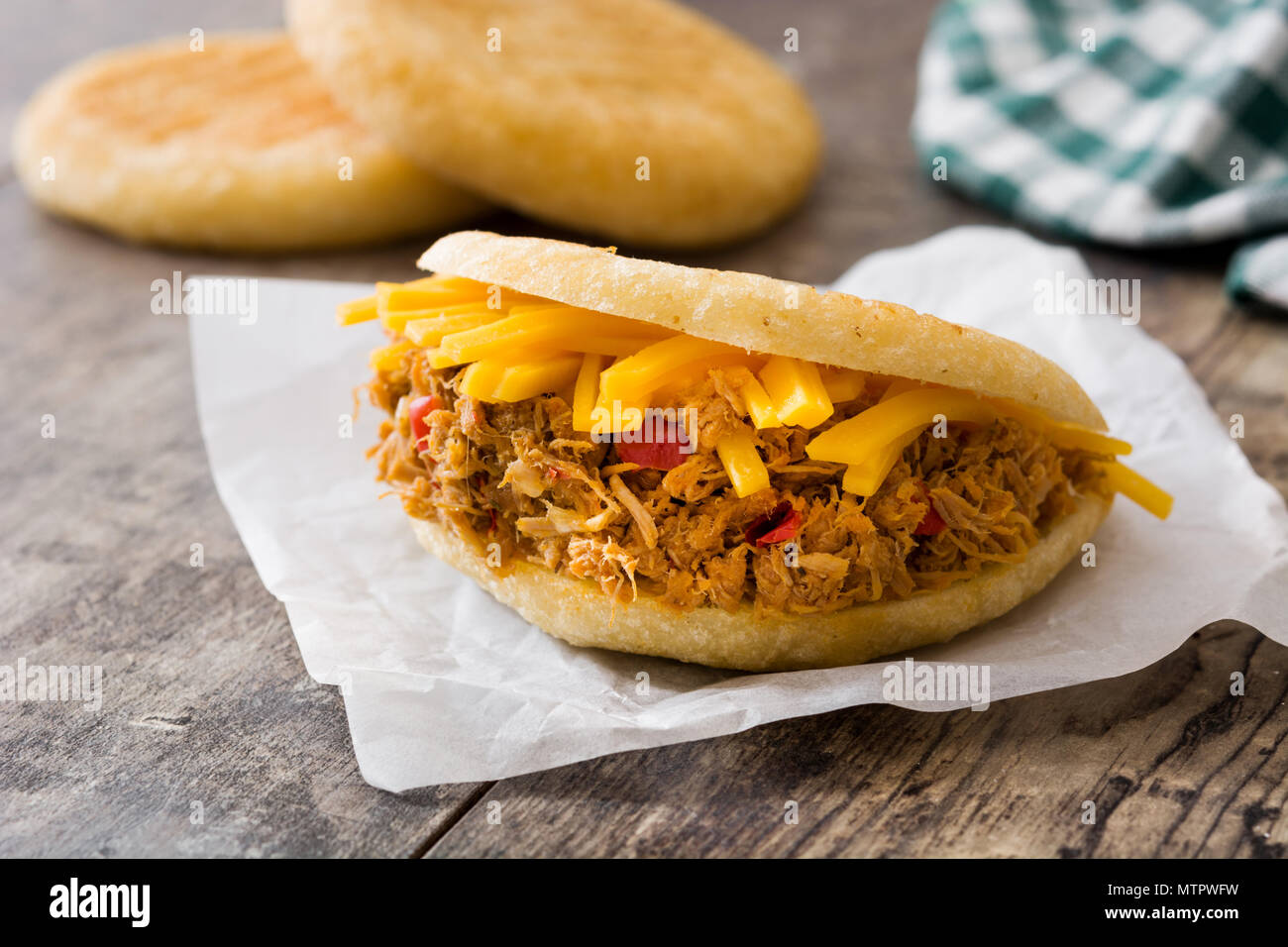 Arepa with shredded beef and cheese on wooden background. Venezuelan ...