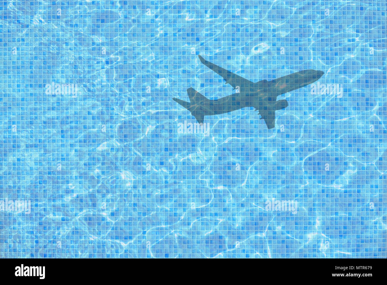 Shadow of leaving airplane takes off over empty pool concept for back to work, school start for example. Stock Photo