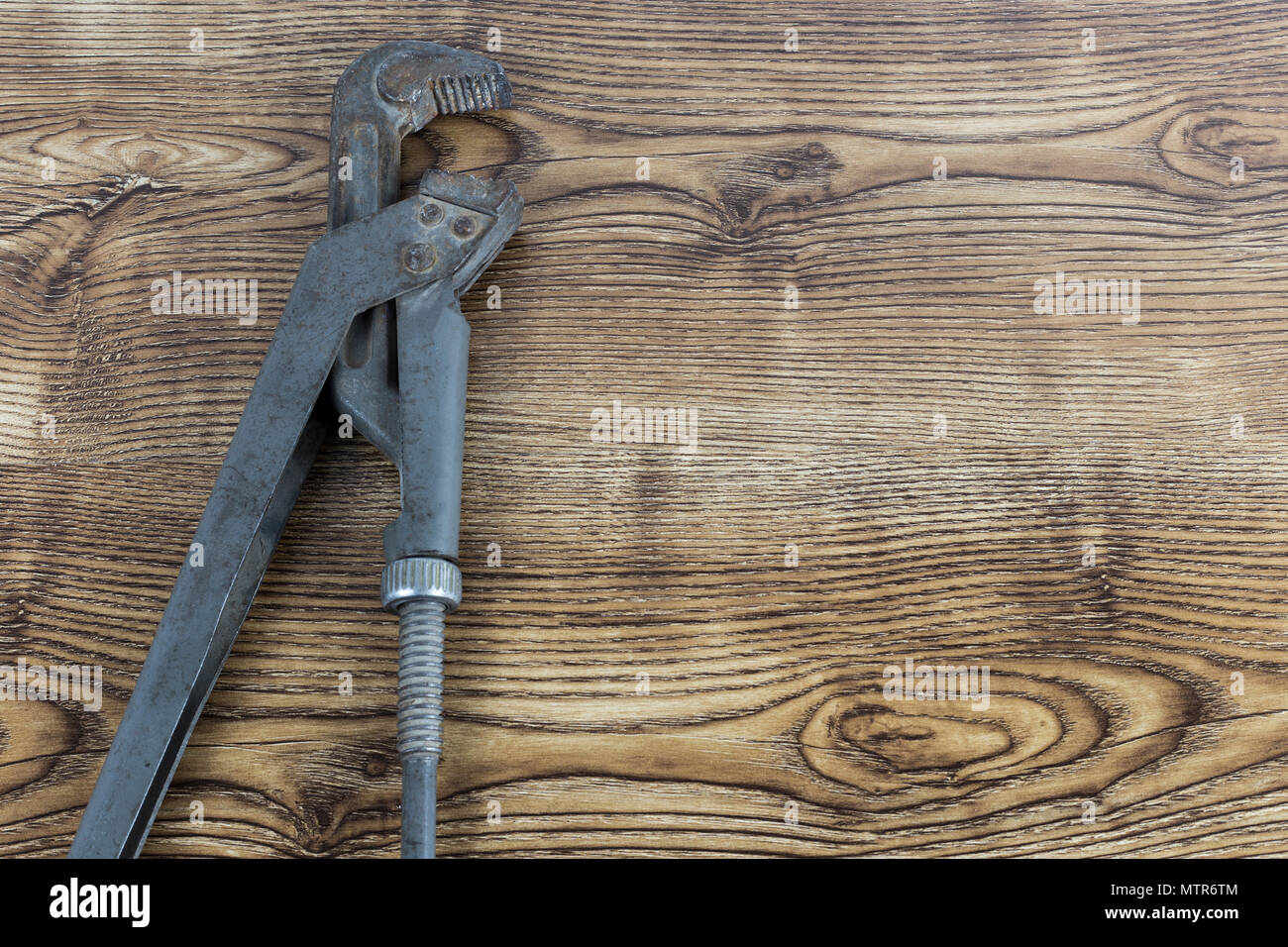 Adjustable gray vintage gas pipe wrench lays on wooden background Stock
