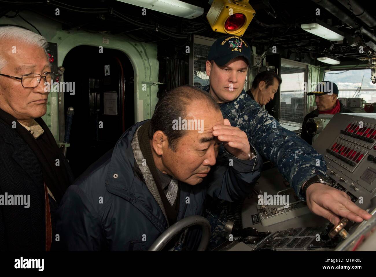 170118-N-NB544-178 SASEBO, Japan (Jan. 18, 2017) Quartermaster 1st Class Matthew Lenerville, from Richardton, N.D., explains bridge equipment on board amphibious assault ship USS Bonhomme Richard (LHD 6) during a tour for Sasebo and Saga city community leaders. Bonhomme Richard, forward-deployed to Sasebo, Japan, is serving forward to provide a rapid-response capability in the event of a regional contingency or natural disaster. (U.S. Navy Photo by Mass Communication Specialist 2nd Class Kyle Carlstrom/Released) Stock Photo