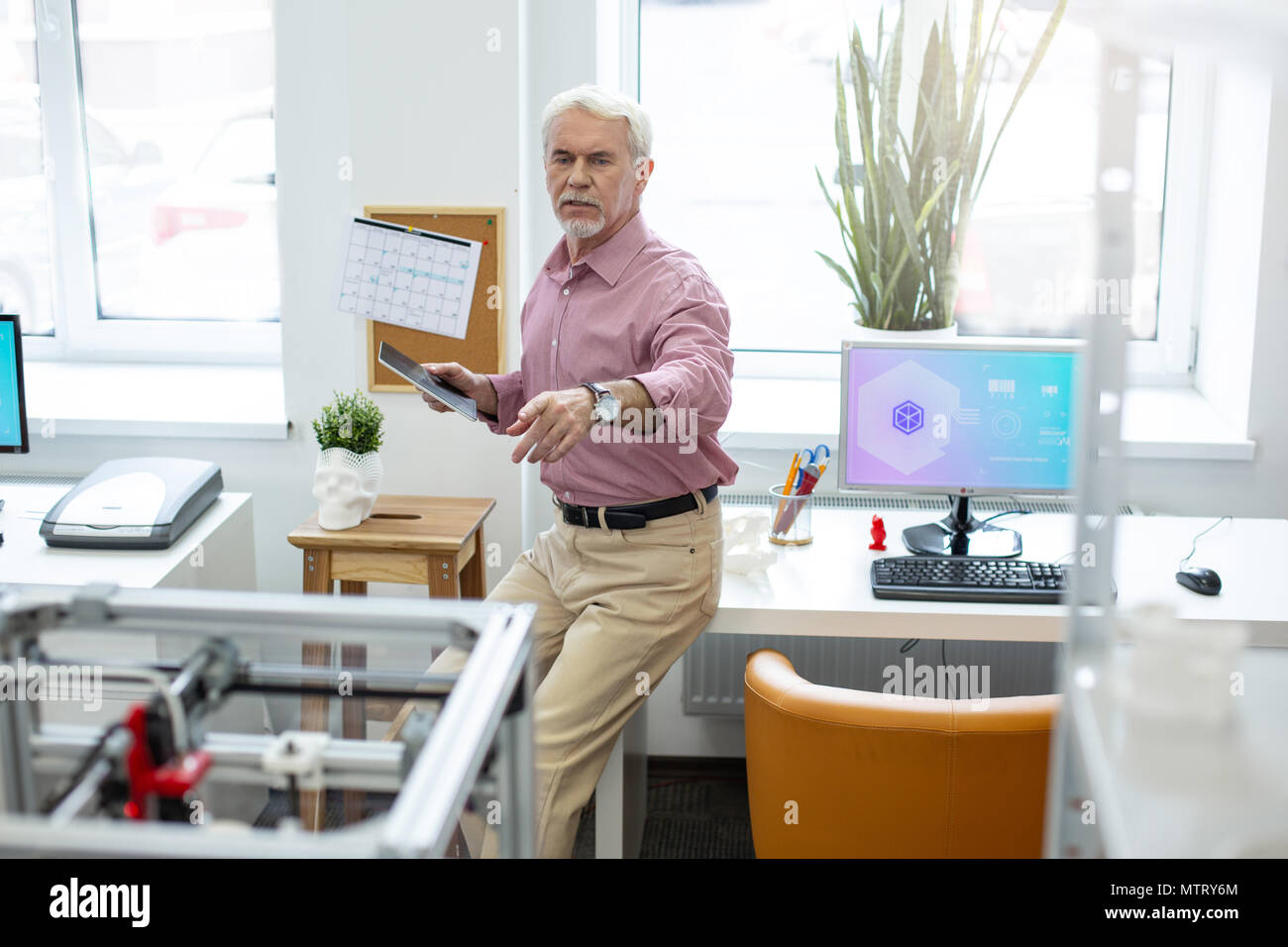 Worried senior man noticing malfunction of 3D printer Stock Photo