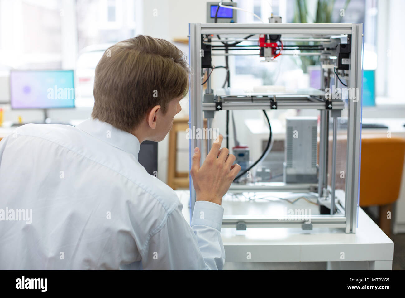 Pleasant young engineer watching 3D printer in action Stock Photo
