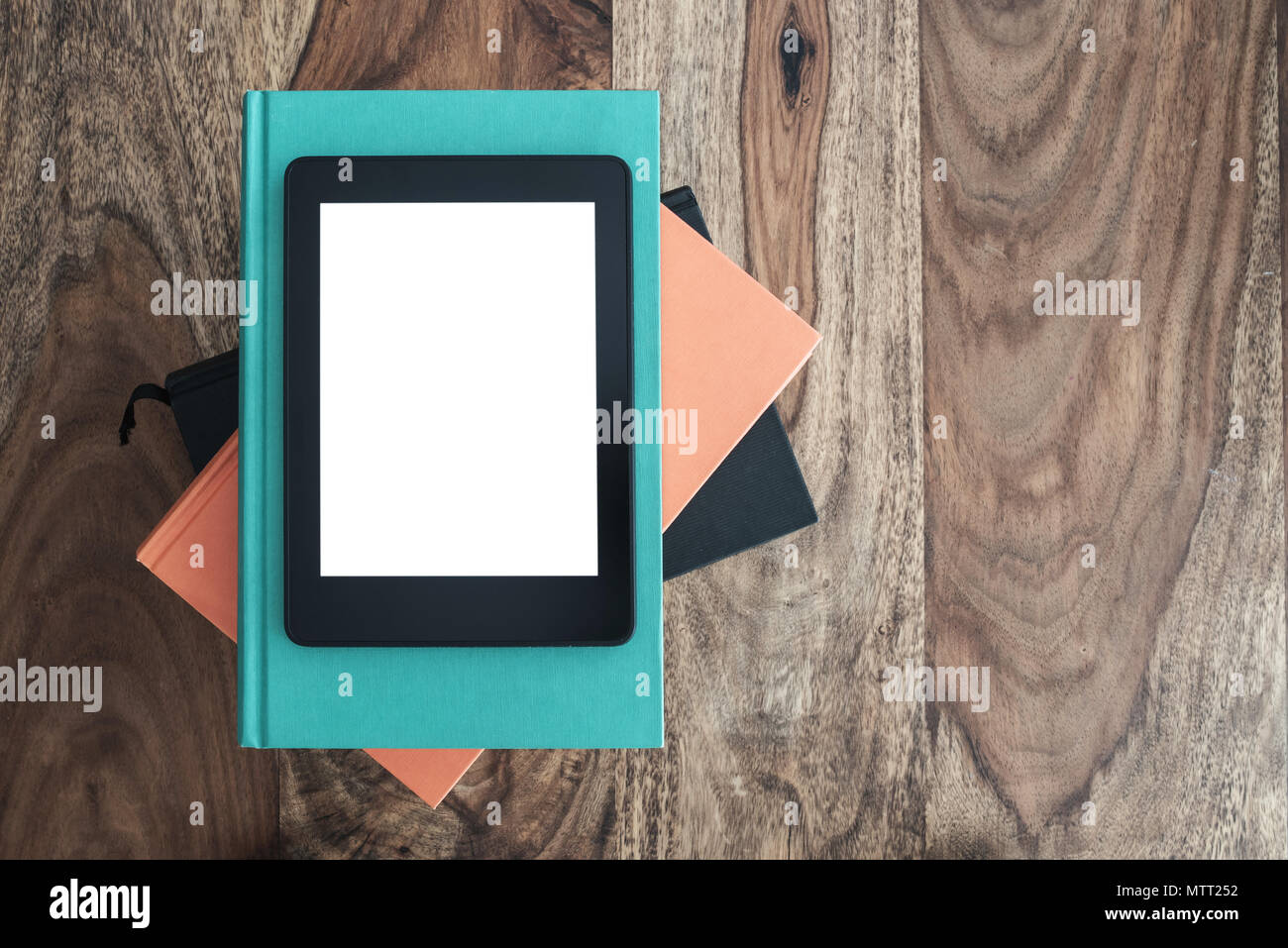 top view of e-book reader on stack of books on wooden table Stock Photo