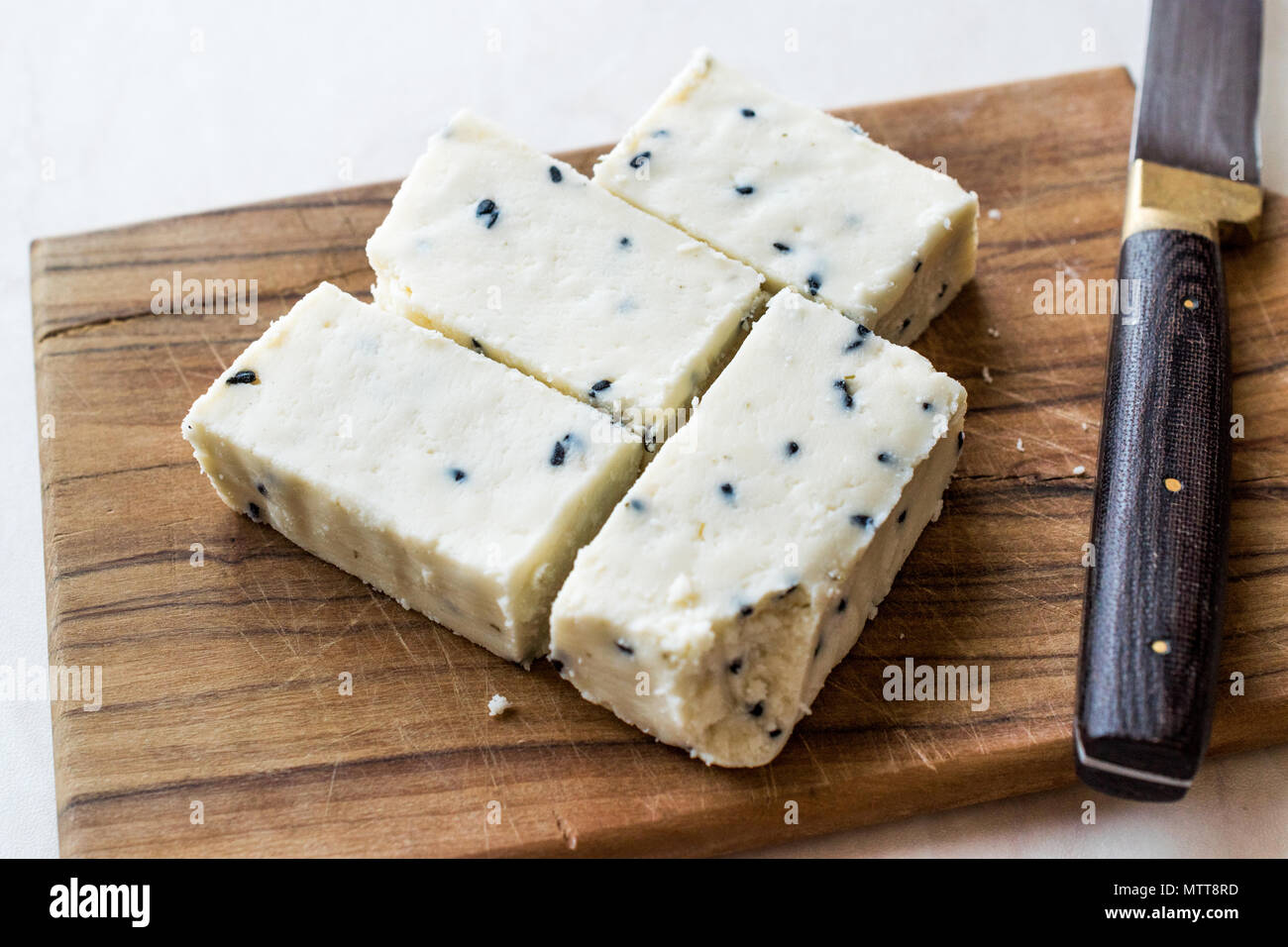 Turkish Feta Cheese with Black Cumin (Sesame) Seeds on Wooden Surface with Knife. Traditional Organic Food. Stock Photo