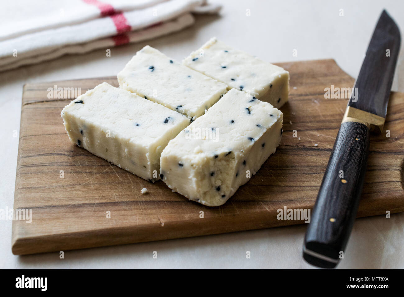 Turkish Feta Cheese with Black Cumin (Sesame) Seeds on Wooden Surface with Knife. Traditional Organic Food. Stock Photo