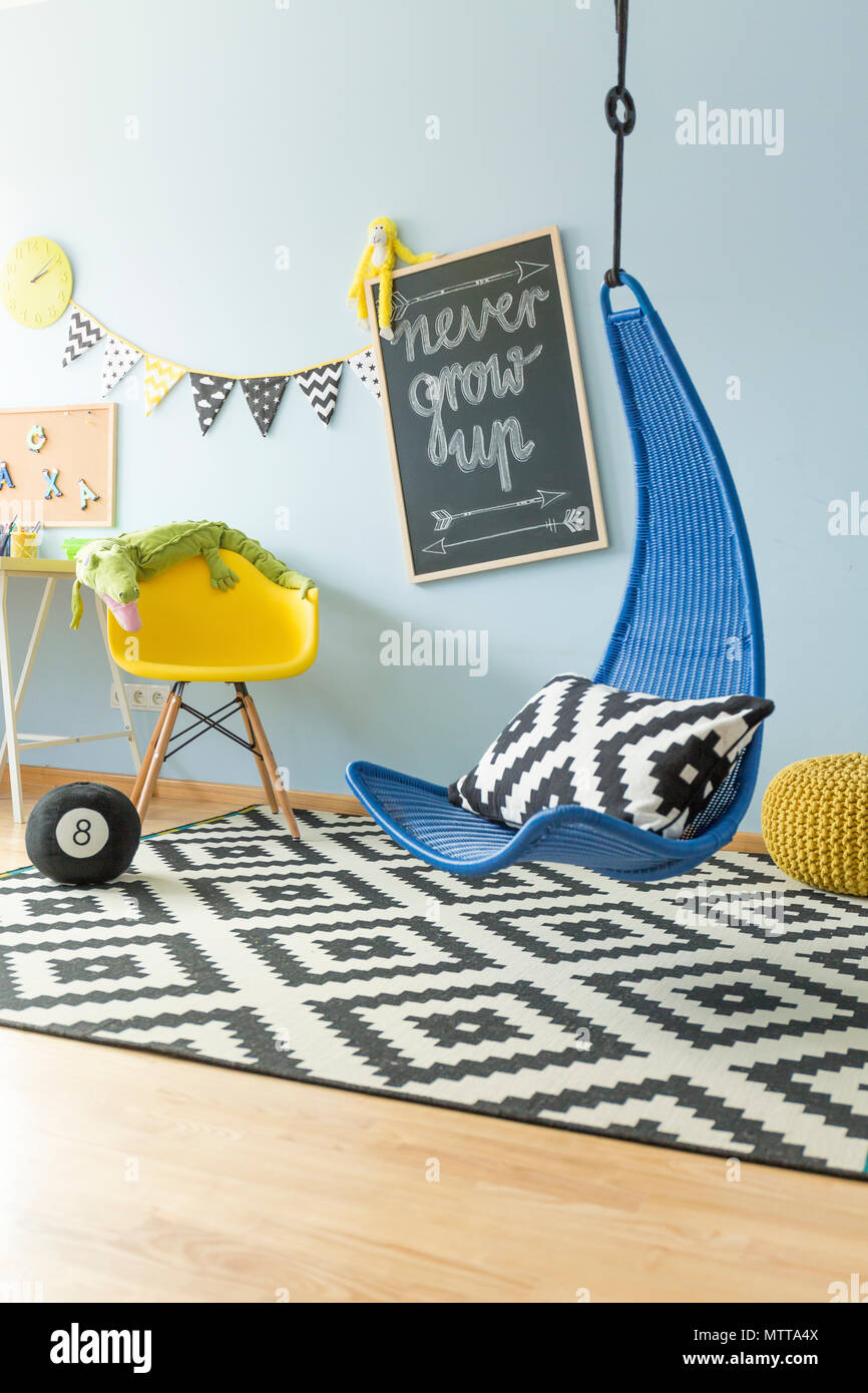 Modern, bright teenager room with navy blue hanging chair and patterned