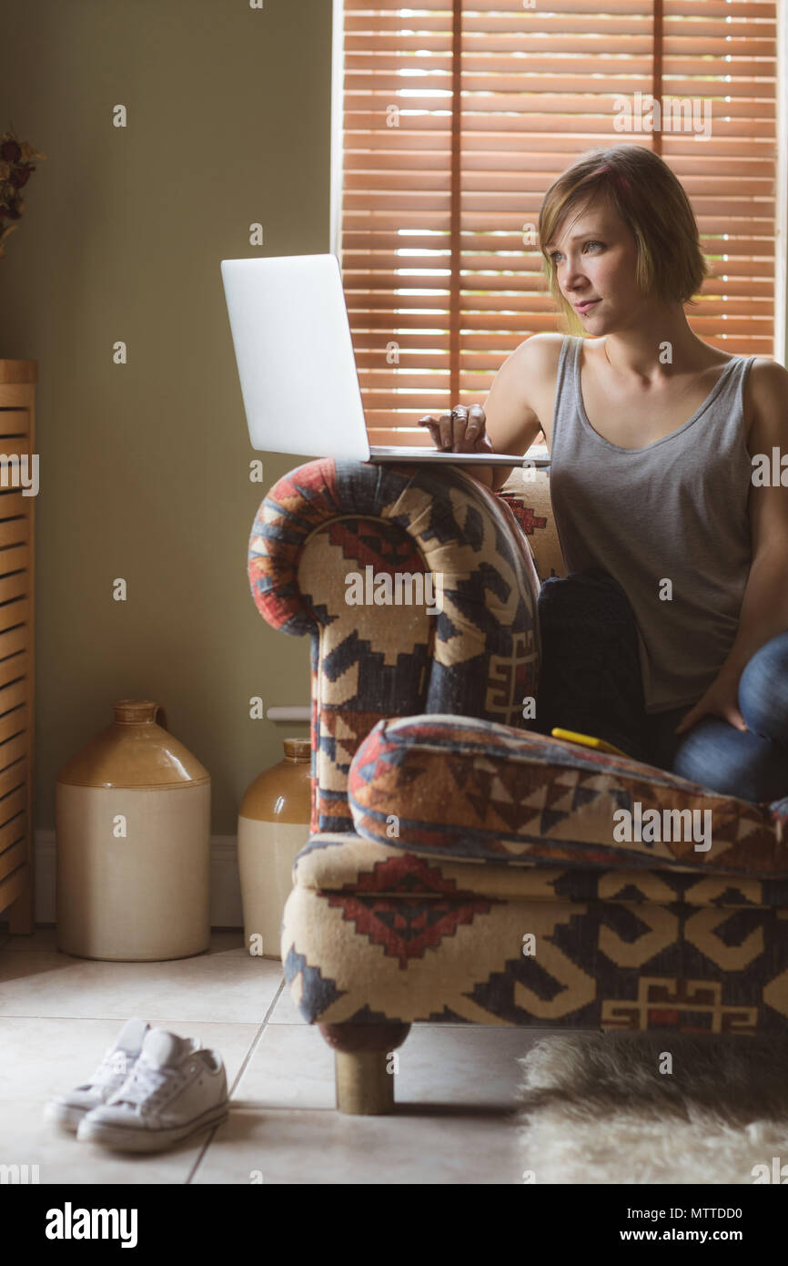 Beautiful woman using laptop on sofa in living room Stock Photo - Alamy