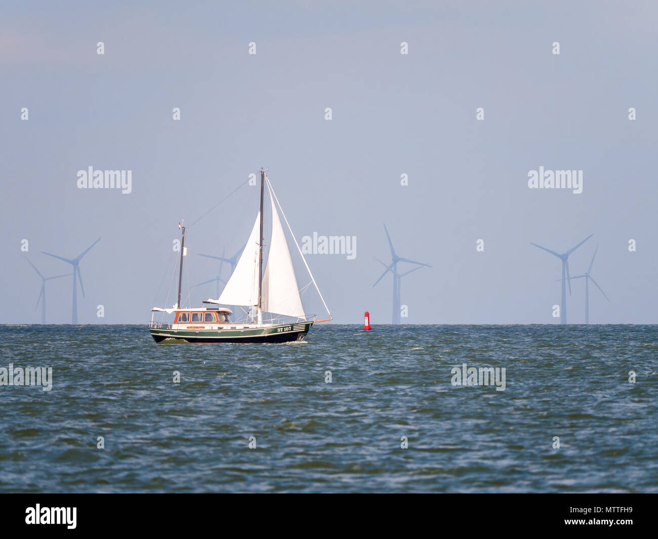 People on sailboat sailing on lake IJsselmeer and wind turbines of wind