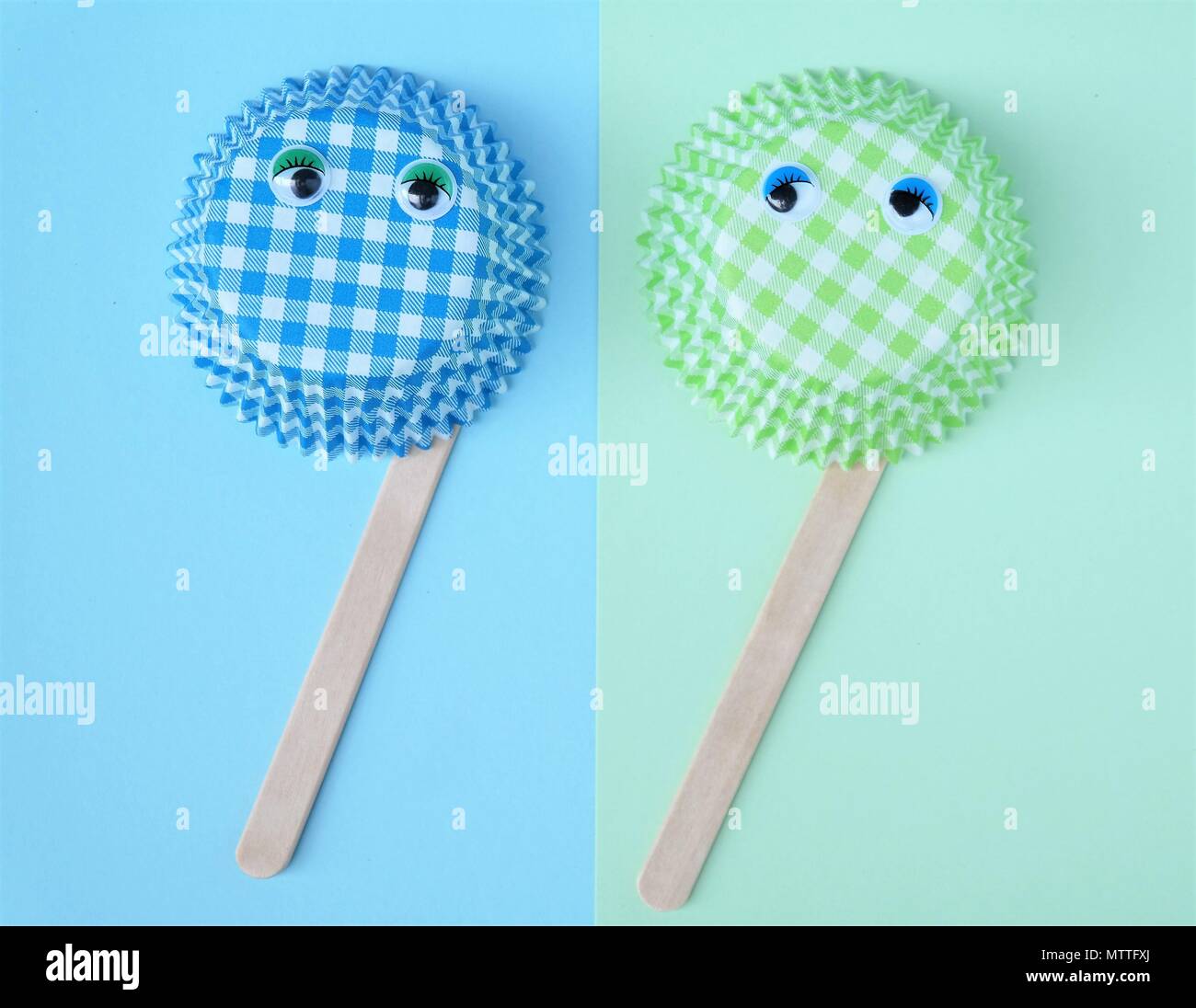 two cupcake molds of paper with wobbly eyes, ice popsicle sticks, simple concept in pastel colors green and blue. Funny creative image and text space Stock Photo