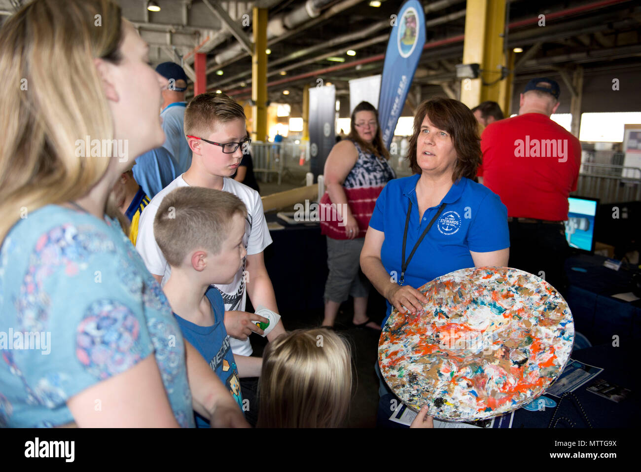 180526-N-IT235-0115 NEW YORK (May 26, 2018) Laura Busch, a natural resources program manager at U.S. Fleet Forces Command’s Fleet Environmental and Readiness Division, explains the shipboard waste process to reduce plastic waste aboard ships at the U.S. Navy’s “Stewards of the Sea: Defending Freedom, Protecting the Environment” exhibit during Fleet Week New York. The Navy employs every means available to mitigate the potential environmental effects of our activities without jeopardizing the safety of our Sailors or impacting our Navy readiness mission. (U.S. Navy photo by Mass Communication Sp Stock Photo