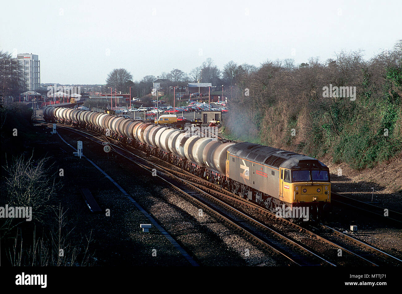 A class 47 diesel locomotive number 47348 powers away from Basingstoke with a lengthy rake of four wheel oil tanks. 14th January 1993. Stock Photo