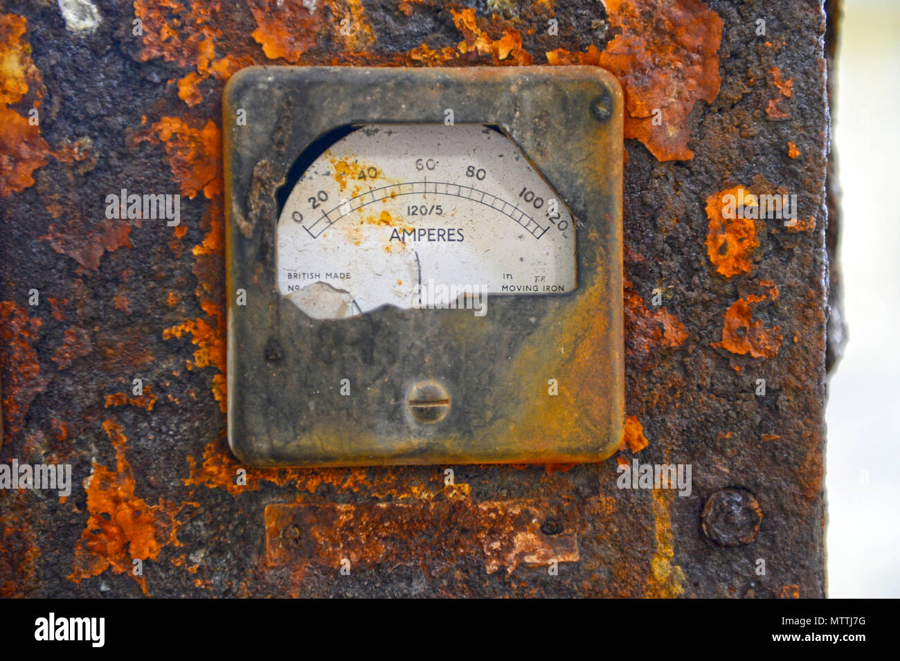 Old control panel rotted away with broken dials and falling apart in an old building with layers of rust Stock Photo