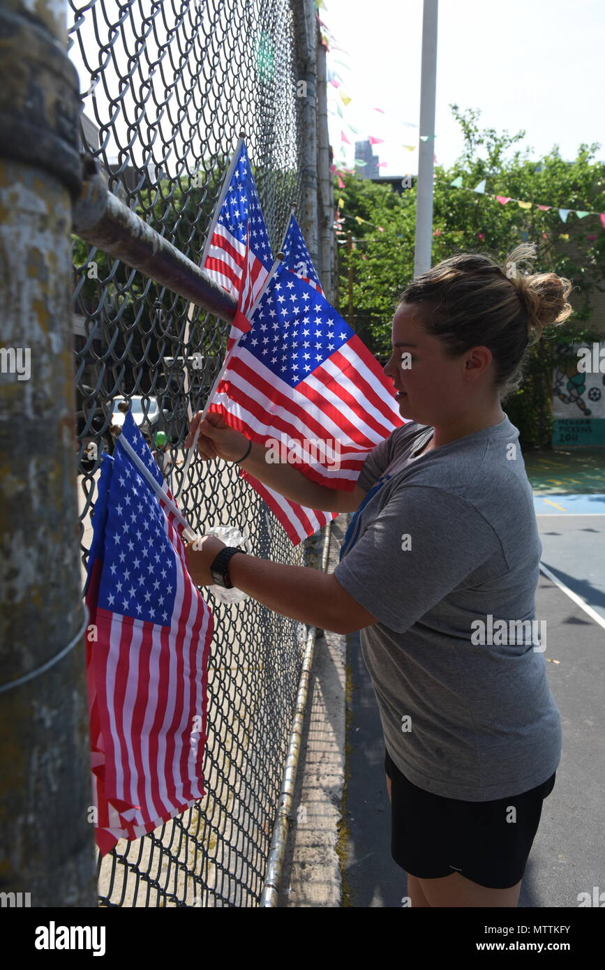 Petty Officer 2nd Class Bethany Hildebrand, stationed aboard the U.S. Coast Guard Cutter Richard Snyder, places flags in the fence at P.S. 111 Adolph S. Ochs, in Manhattan, N.Y., as part of the decorations for Project Hope during Fleet Week New York, May 26, 2018. (U.S. Coast Guard photo by Petty Officer 3rd Class Frank Iannazzo-Simmons) Stock Photo