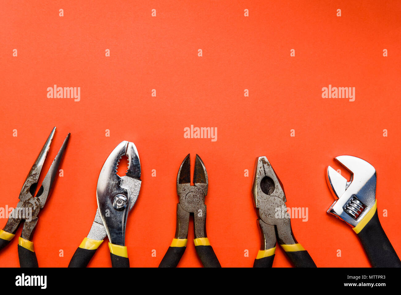 Various Used Pliers Tools on a orange textured background with space for text Stock Photo