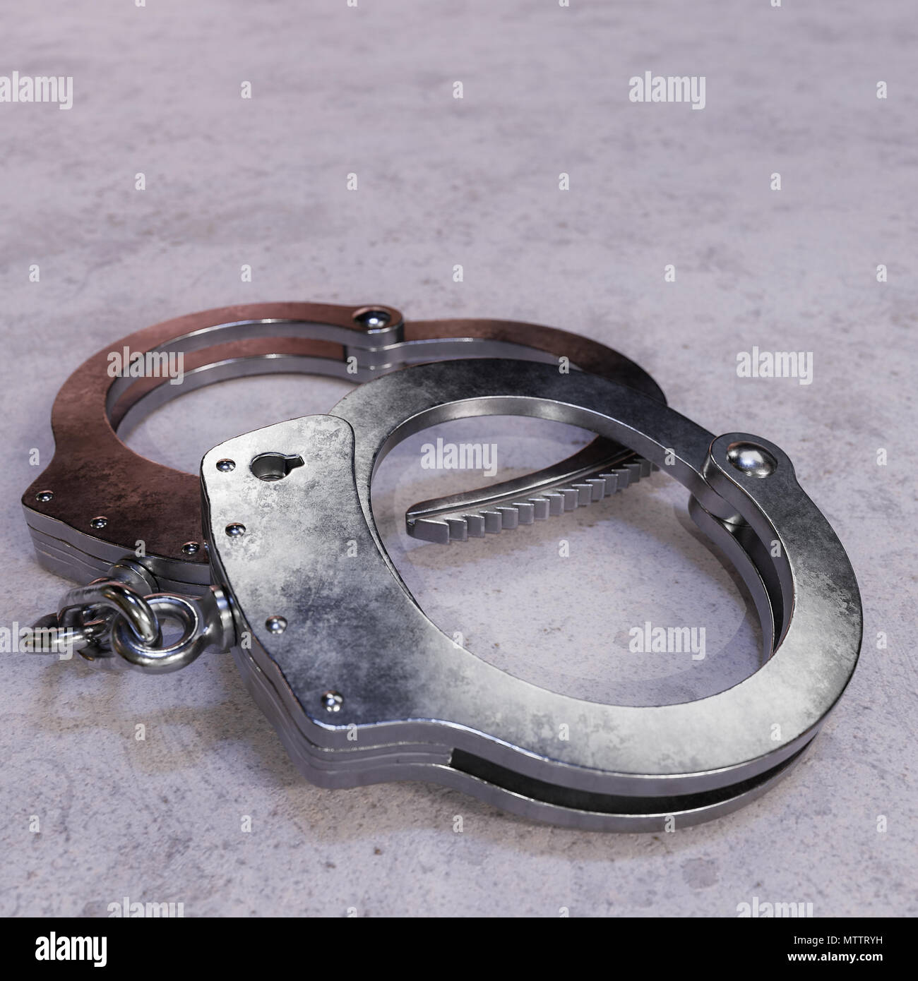 Pair of high security handcuffs resting on an uninviting concrete surface. Stock Photo