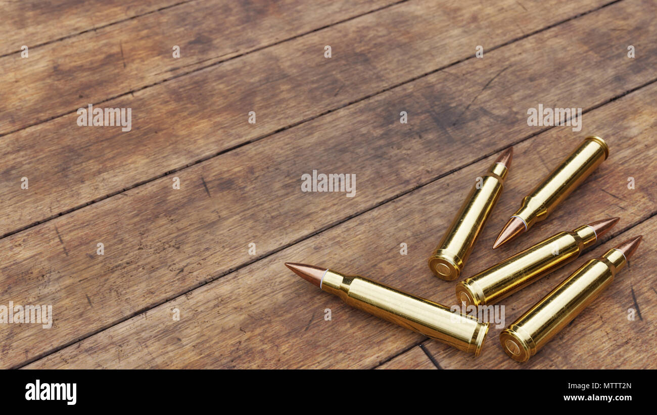 Several rounds of rifle ammunition on aged wooden floor boards. Stock Photo