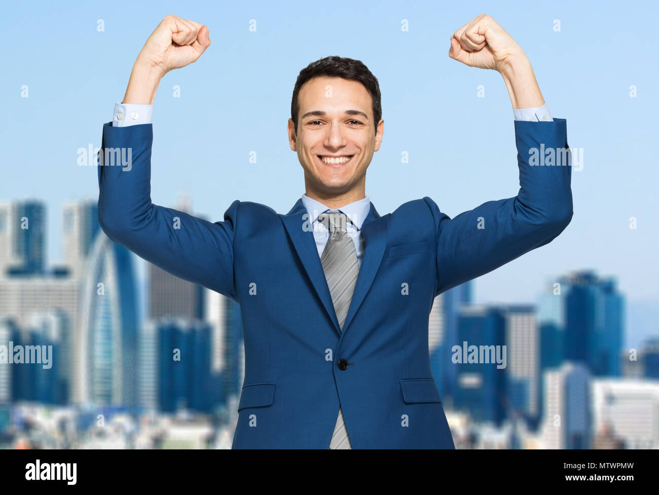 Businessman smiling and raising his fist in the air, with office ...