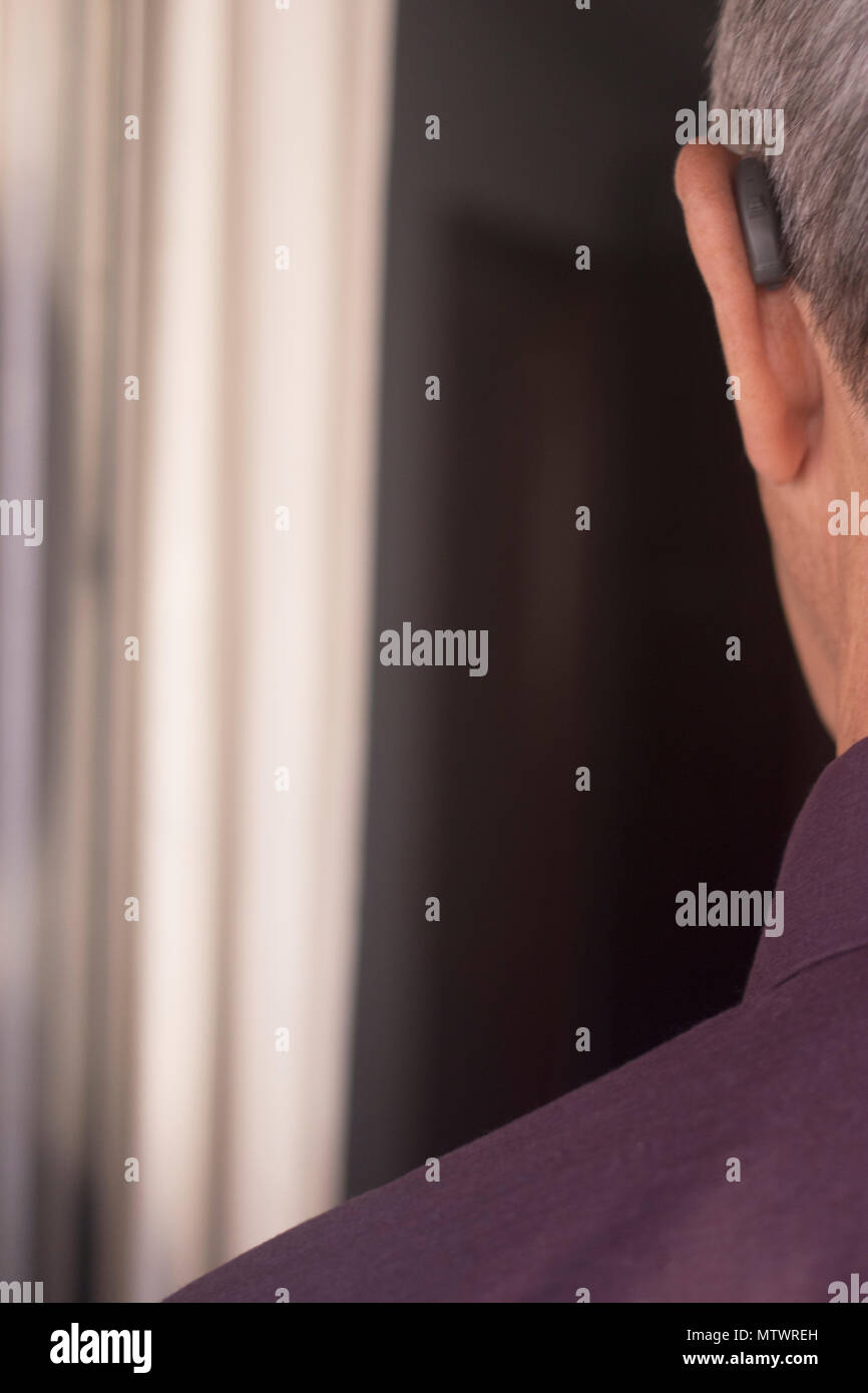 Deaf senior citizen man wearing modern digital high technology hearing ...