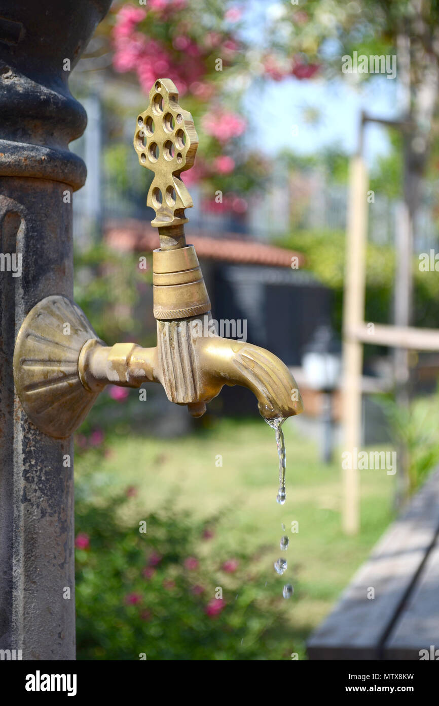 The bronze tap with flowing water on a hot summer day. Vintage faucet. Stock Photo