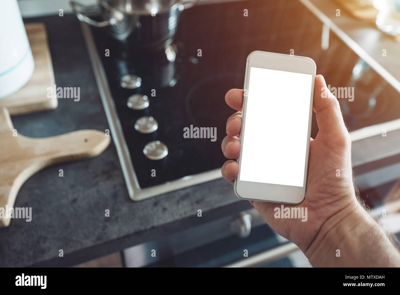 Internet of things, smartphone mock up screen in male hand. Smart home kitchen appliance connecting with mobile phone and exchanging data Stock Photo