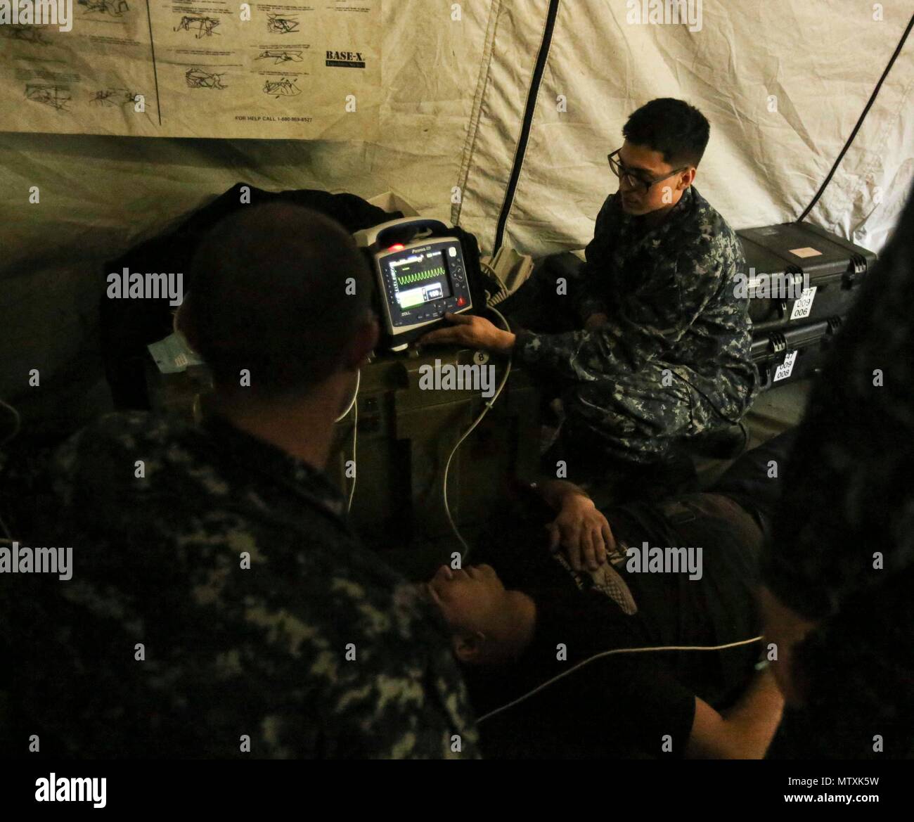 A Navy corpsman demonstrates how to use a defibrillator on a notional patient with heart palpitations as part of Naval Medical Augmentation Program training at Camp Lejeune, N.C., Jan. 26, 2017. The training is used to strengthen communication skills in an austere environment and increase combat readiness. The Sailors are with 2nd Medical Battalion. (U.S. Marine Corps photo by Cpl. Ashley Lawson) Stock Photo