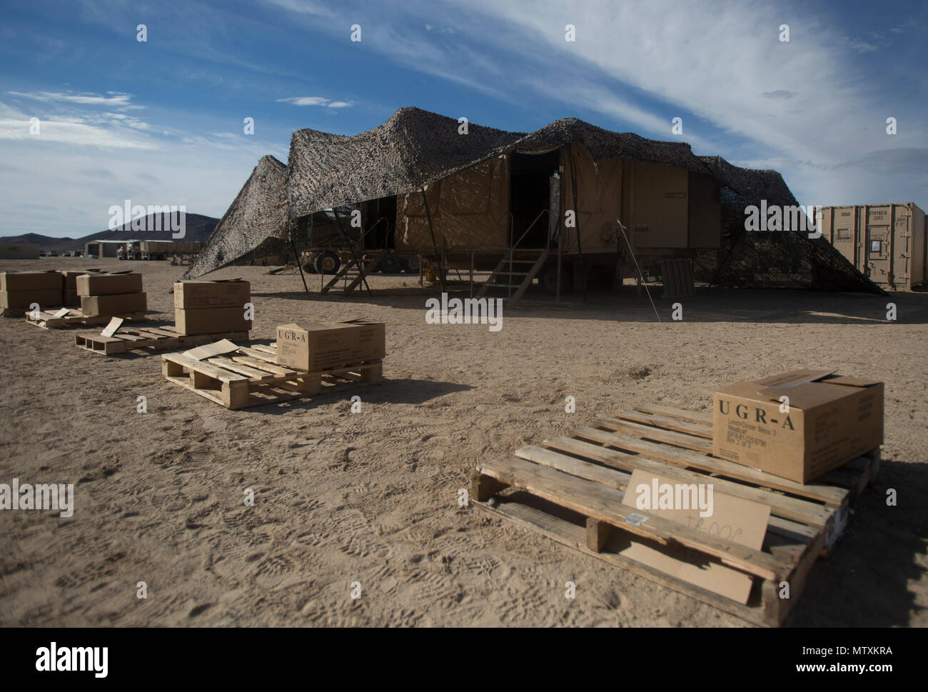 An Army field kitchen is covered in camouflage netting during a