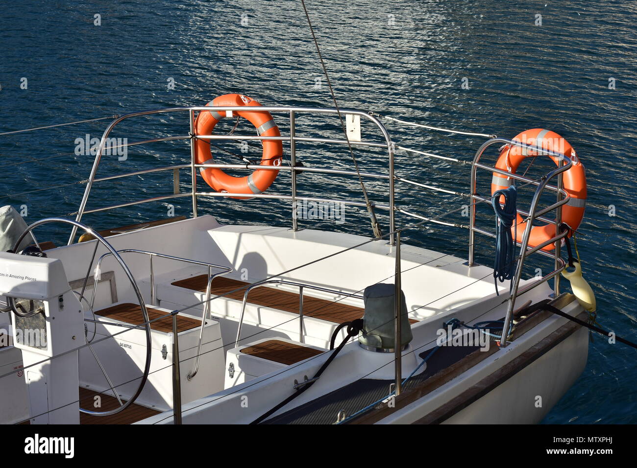 Stern of white sail boat with stainless steel steering wheel and