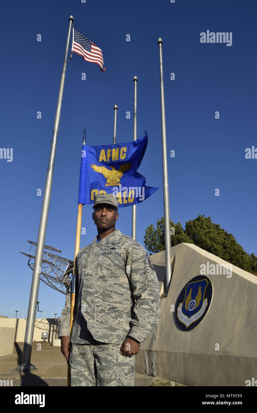 Master Sgt. Teodros Rembert, Oklahoma City Air Logistics Complex first sgt., stands near the base flag pole with the unit guidon prior to an official retreat ceremony Jan. 24, 2017, Tinker Air Force Base, Oklahoma. OC-ALC is an Air Force Materiel Command unit as noted at the top of the guidon as well as the AFMC badge featured on the wall behind. (U.S. Air Force photo/Greg L. Davis) Stock Photo
