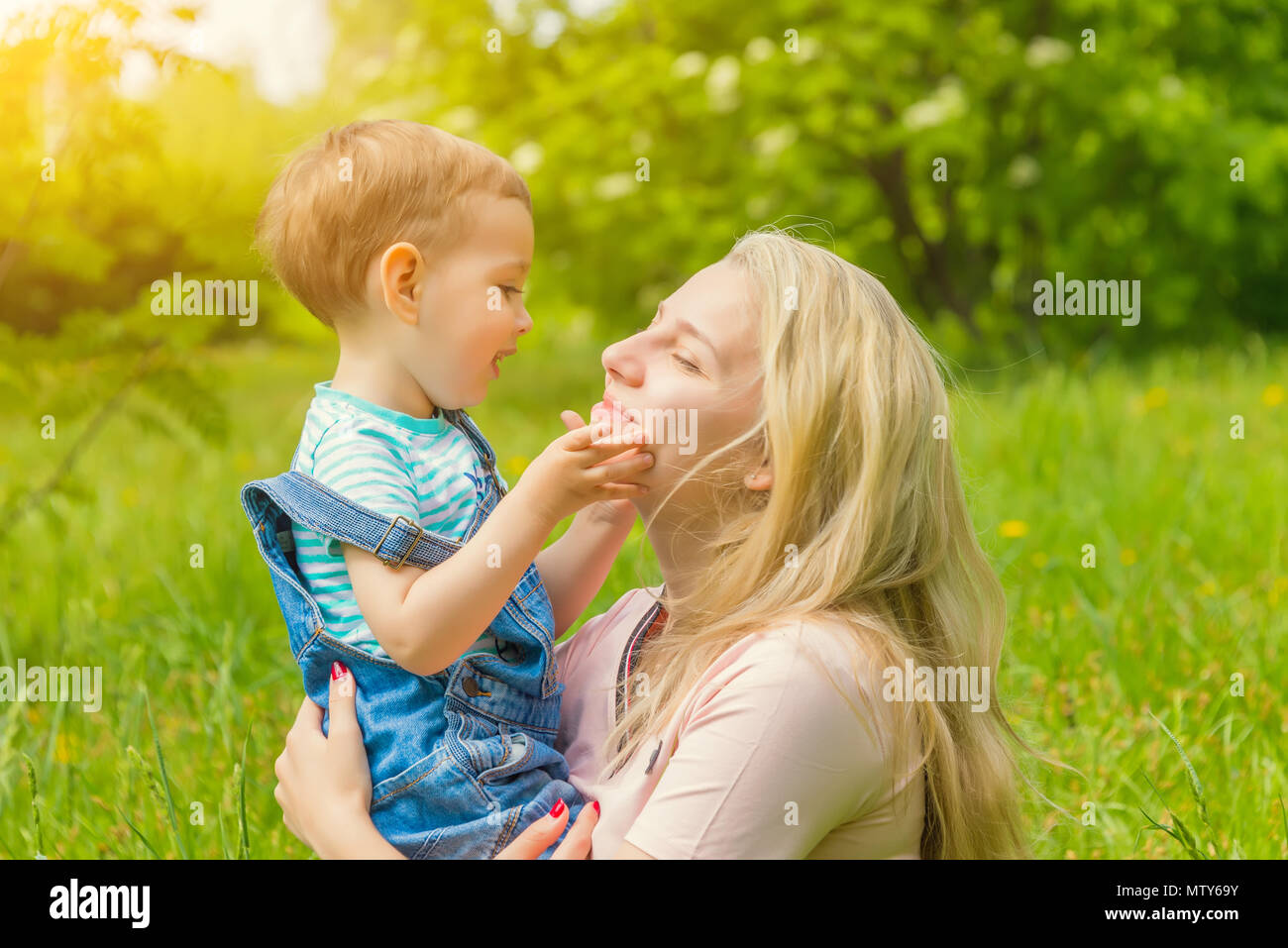 mother and child in nature in the Park, resting on the green grass in ...
