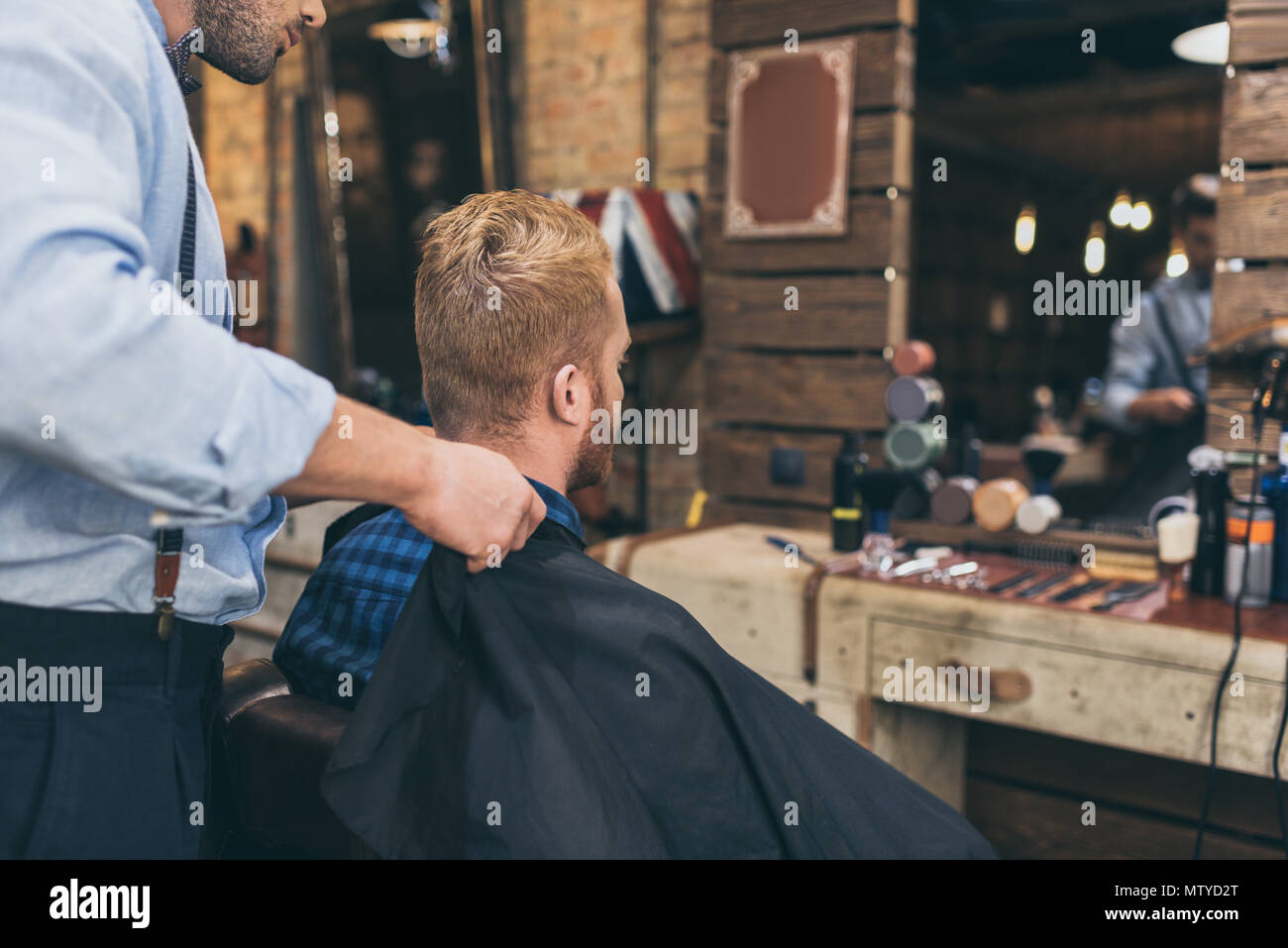 Barber standing with customer that sitting in front of mirror in barber ...