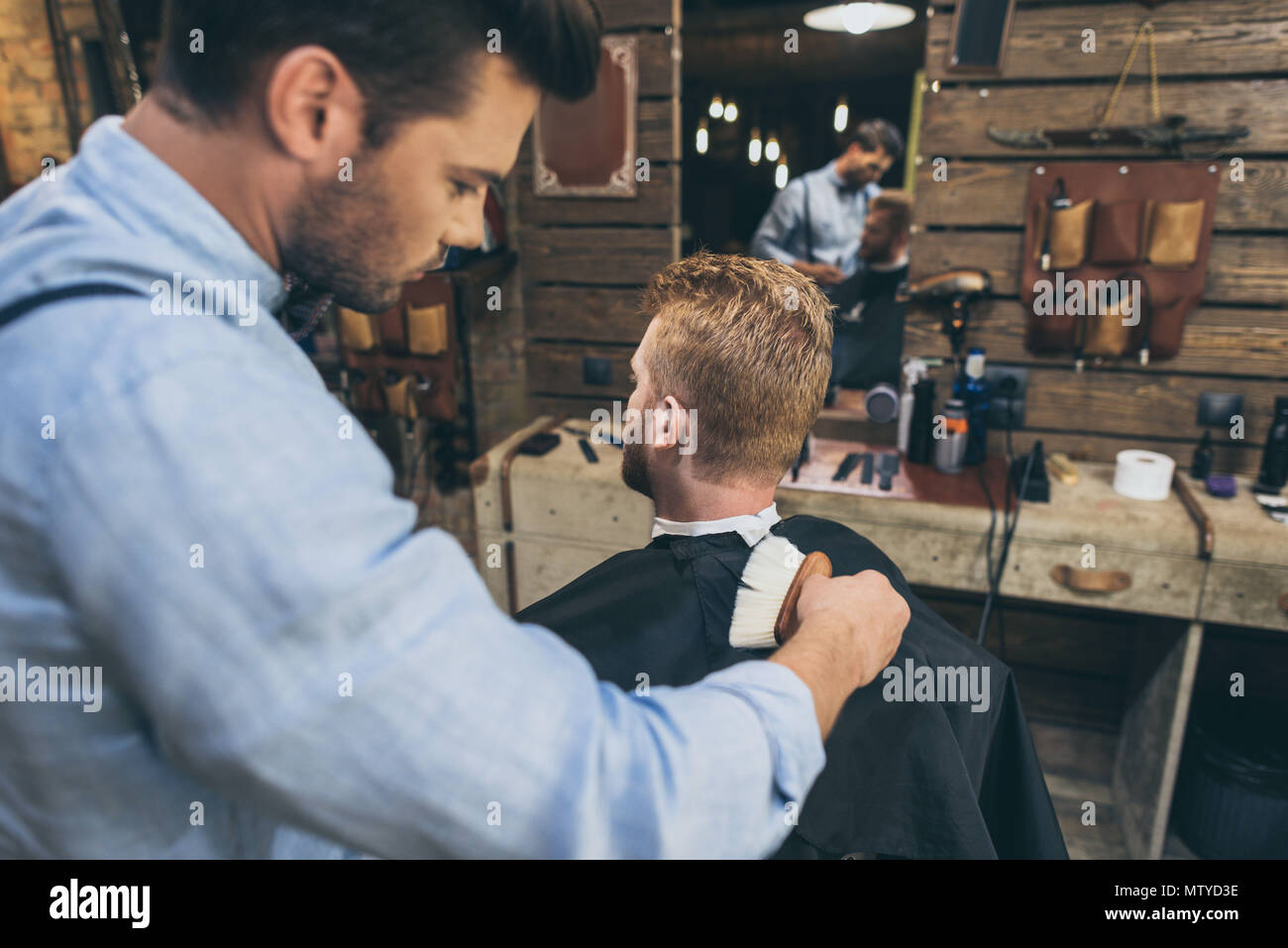 Handsome bearded man is getting hairstyle by hairdresser at barber shop Stock Photo