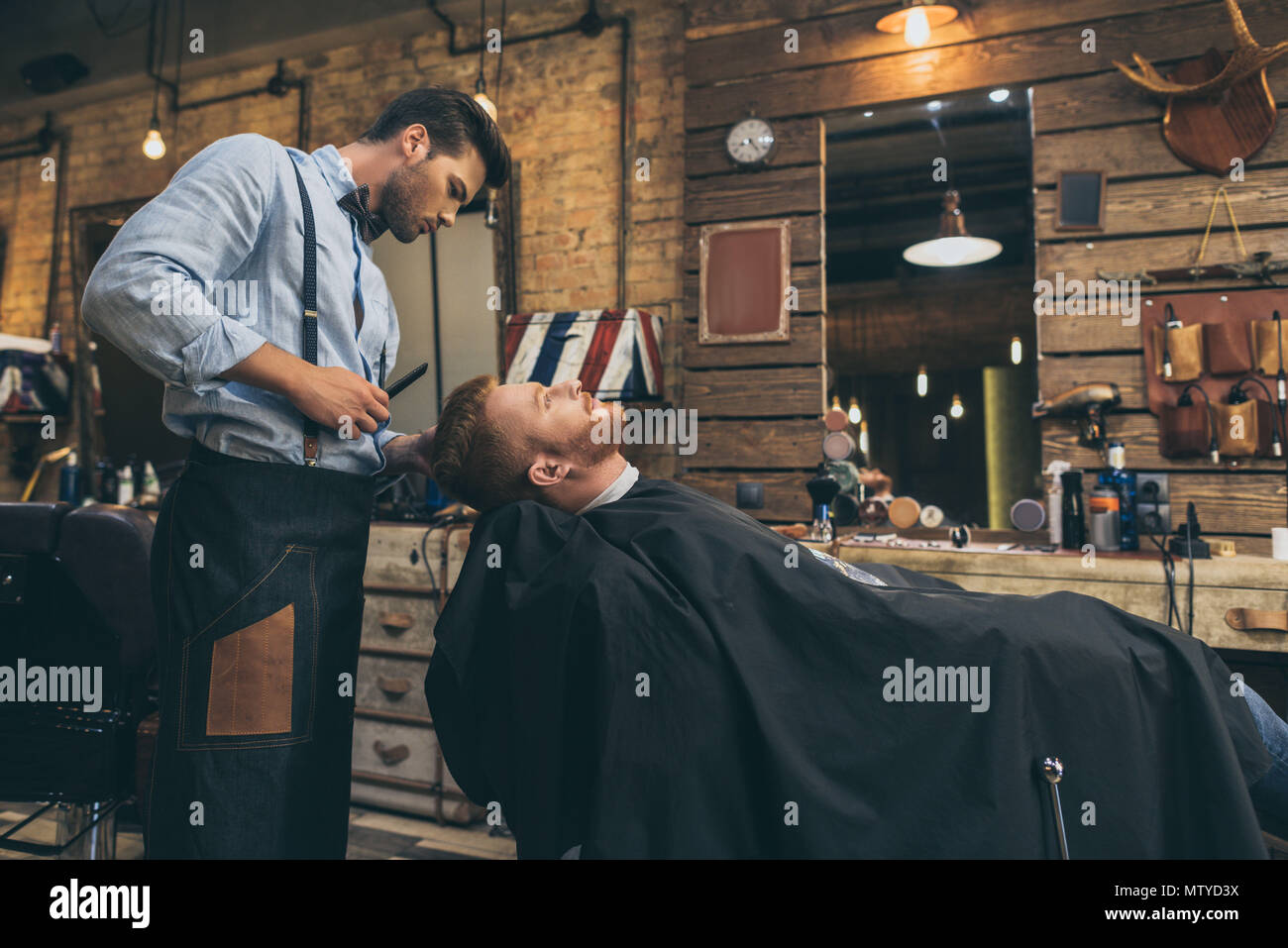 Male barber cutting hair of customer in barber shop Stock Photo