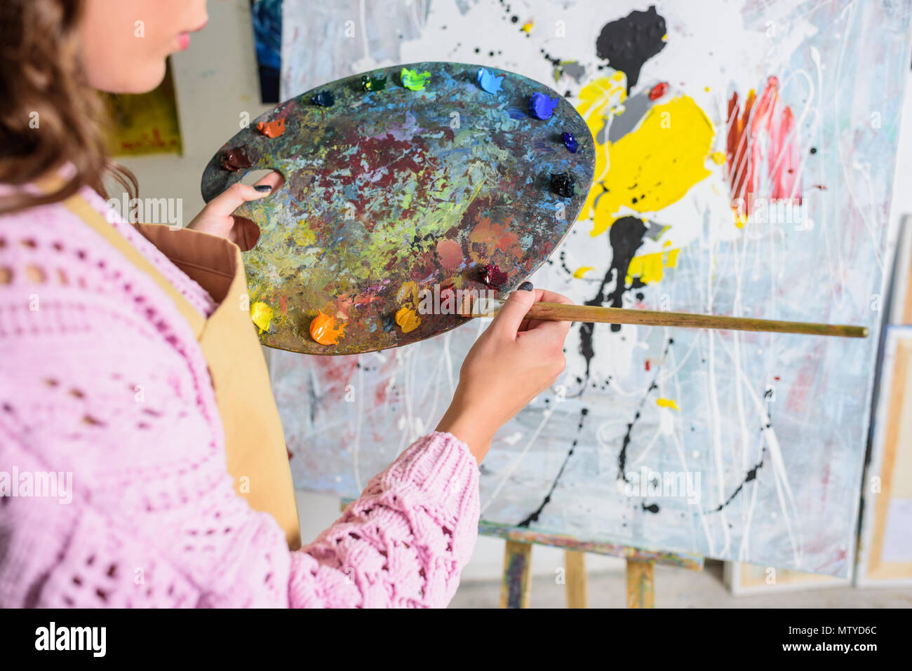cropped image of female artist taking paint from palette in workshop Stock Photo