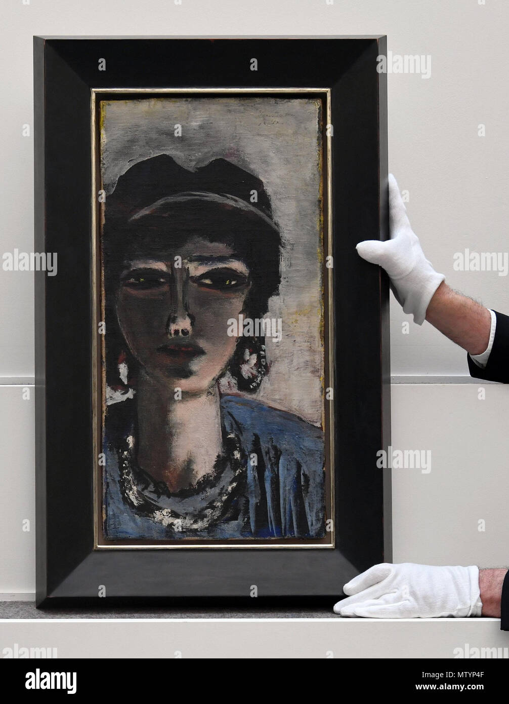 31 May 2018, Germany, Berlin: An employee at Villa Grisebach holding the paiting "Die Aegypterin" (lit. The Egyptian Woman) by Max Beckmann on a pedestal before the auction. Its value is estimated at between 1.5 and 2 million euros. Photo: Soeren Stache/dpa Stock Photo