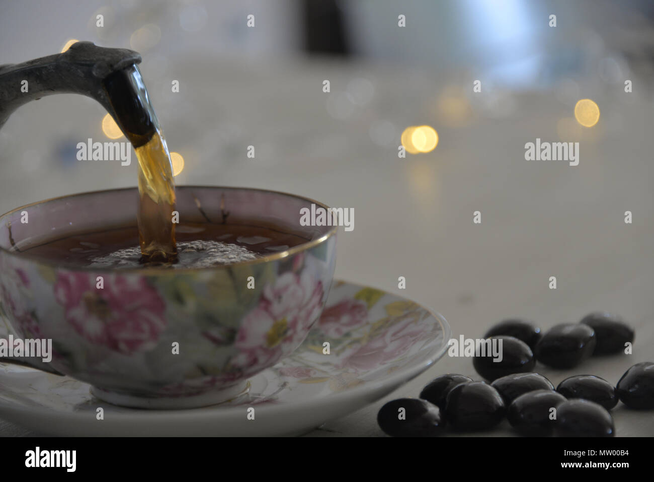 Pouring tea into a tea cup and chocolate confectionary Stock Photo