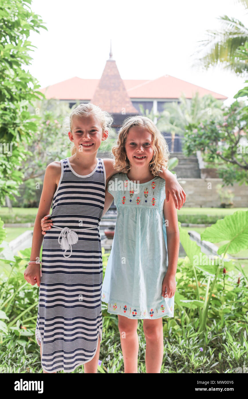 Portrait of two girls with their arm around each other in front of a temple, Ubud, Bali, Indonesia Stock Photo