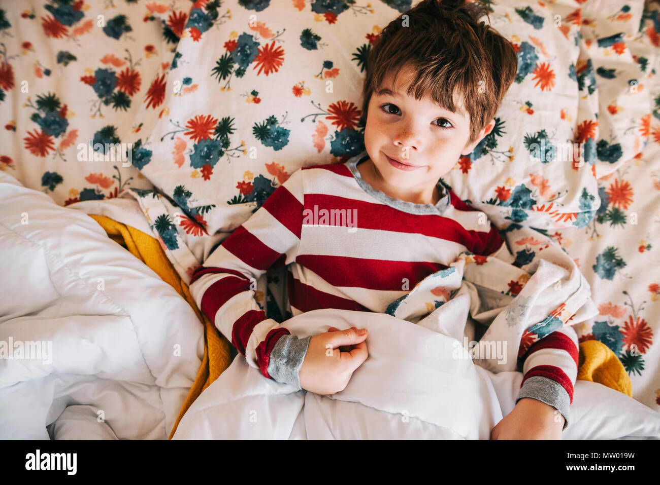 Smiling boy lying in bed Stock Photo