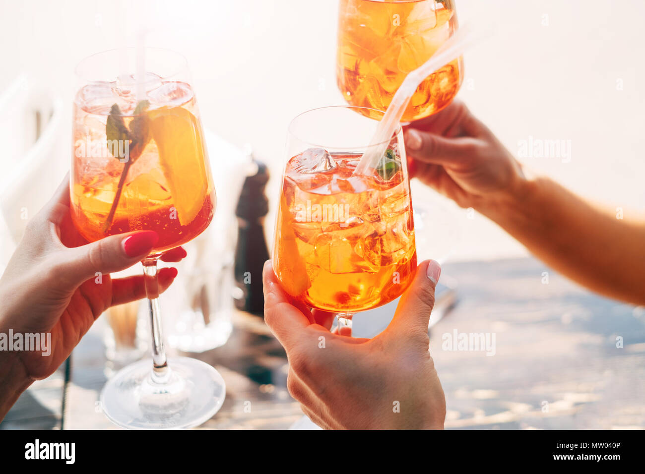 Three women making a celebratory toast with aperol spritz cocktails Stock Photo