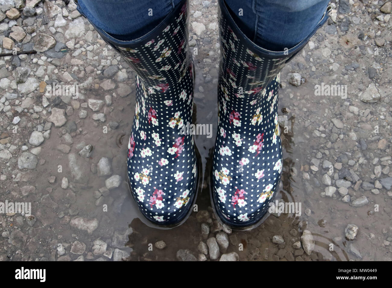 Woman wearing wellington boots standing in a puddle of water Stock Photo