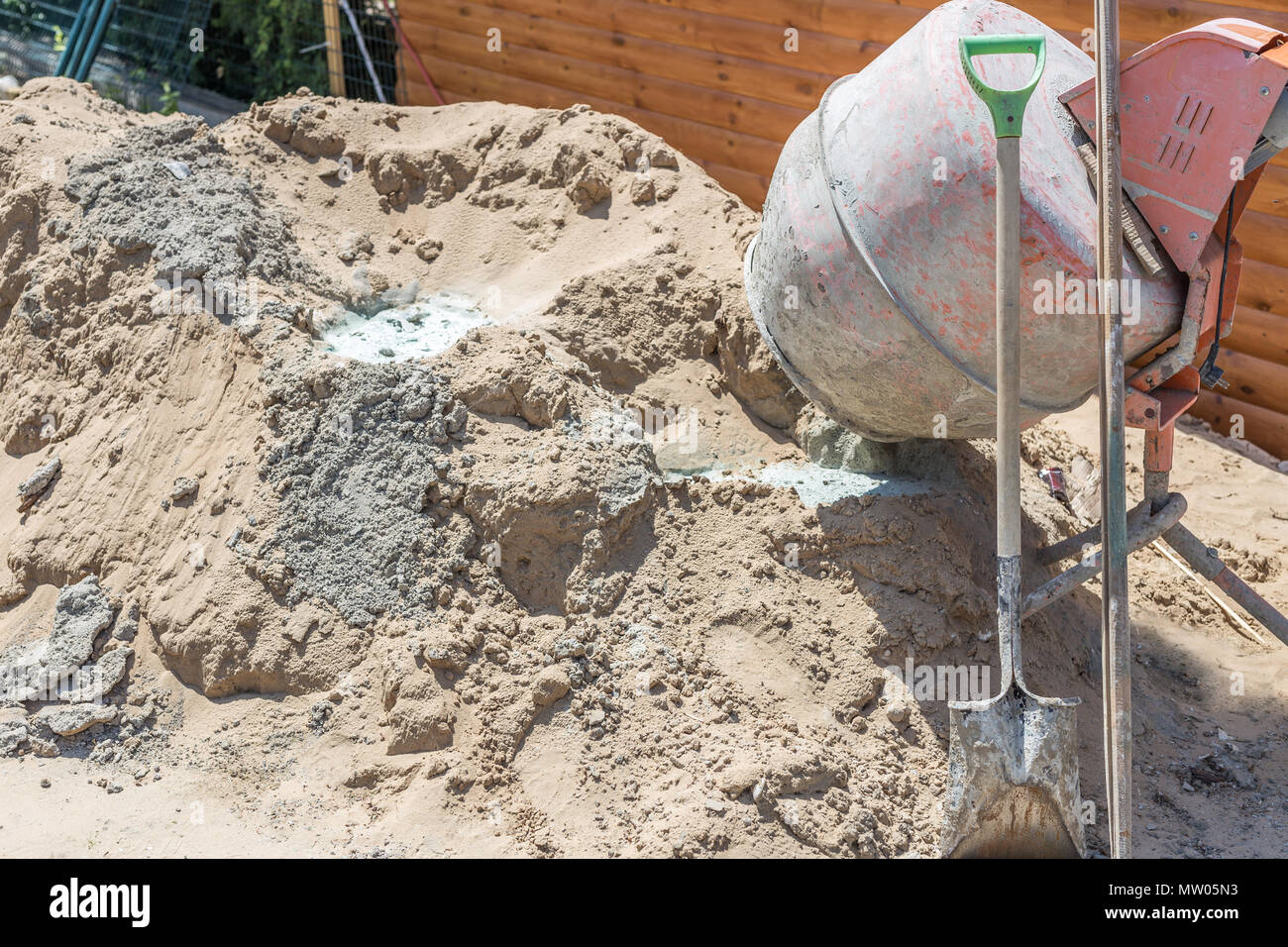 Old dirty concretemixer near sand heap at small construction site