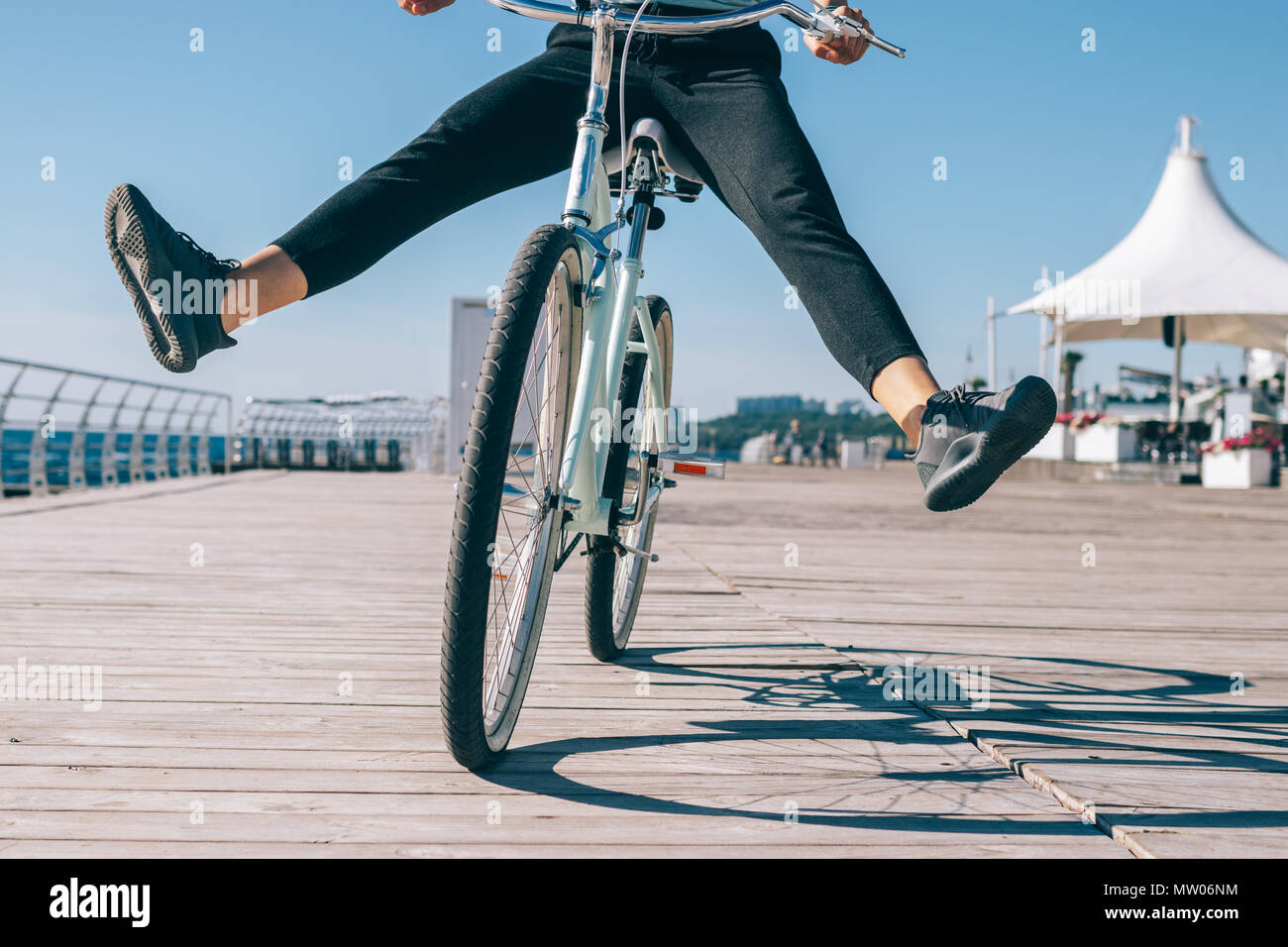 Young woman having fun while cycling along the promenade on a sunny day. Girl riding a bike with