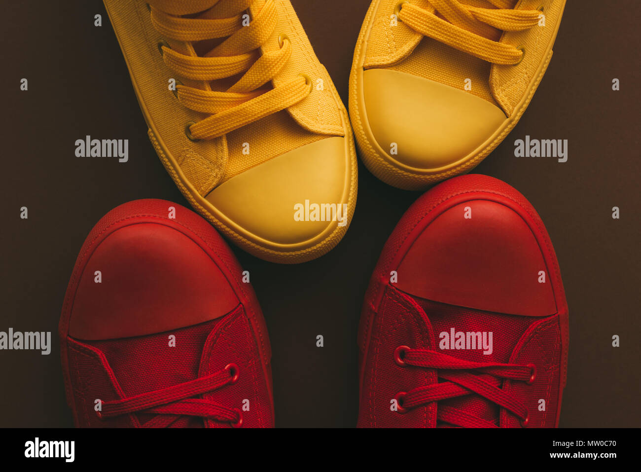 Young couple on a love date, conceptual image. Top view of two pair of casual sneakers, yellow and red, from above close to and facing each other like Stock Photo