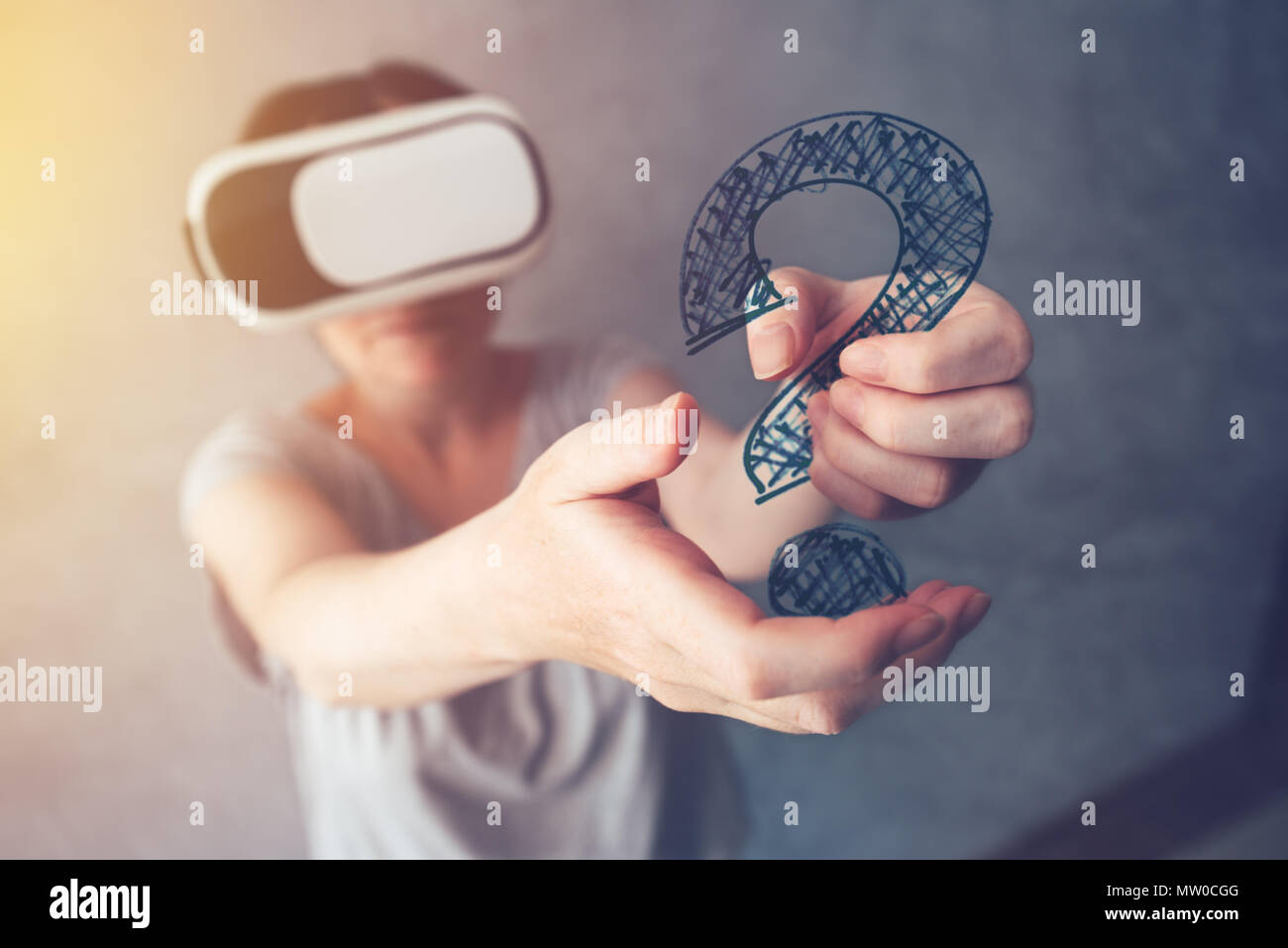 Woman with VR headset holding question mark, female person immersed in virtual reality Stock Photo