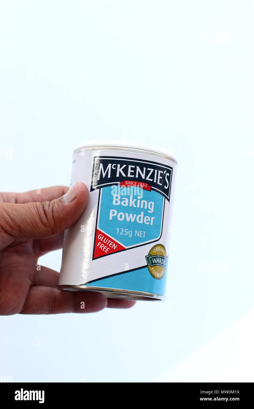Close up image of left hand holding McKenzie's Baking Powder on white background Stock Photo