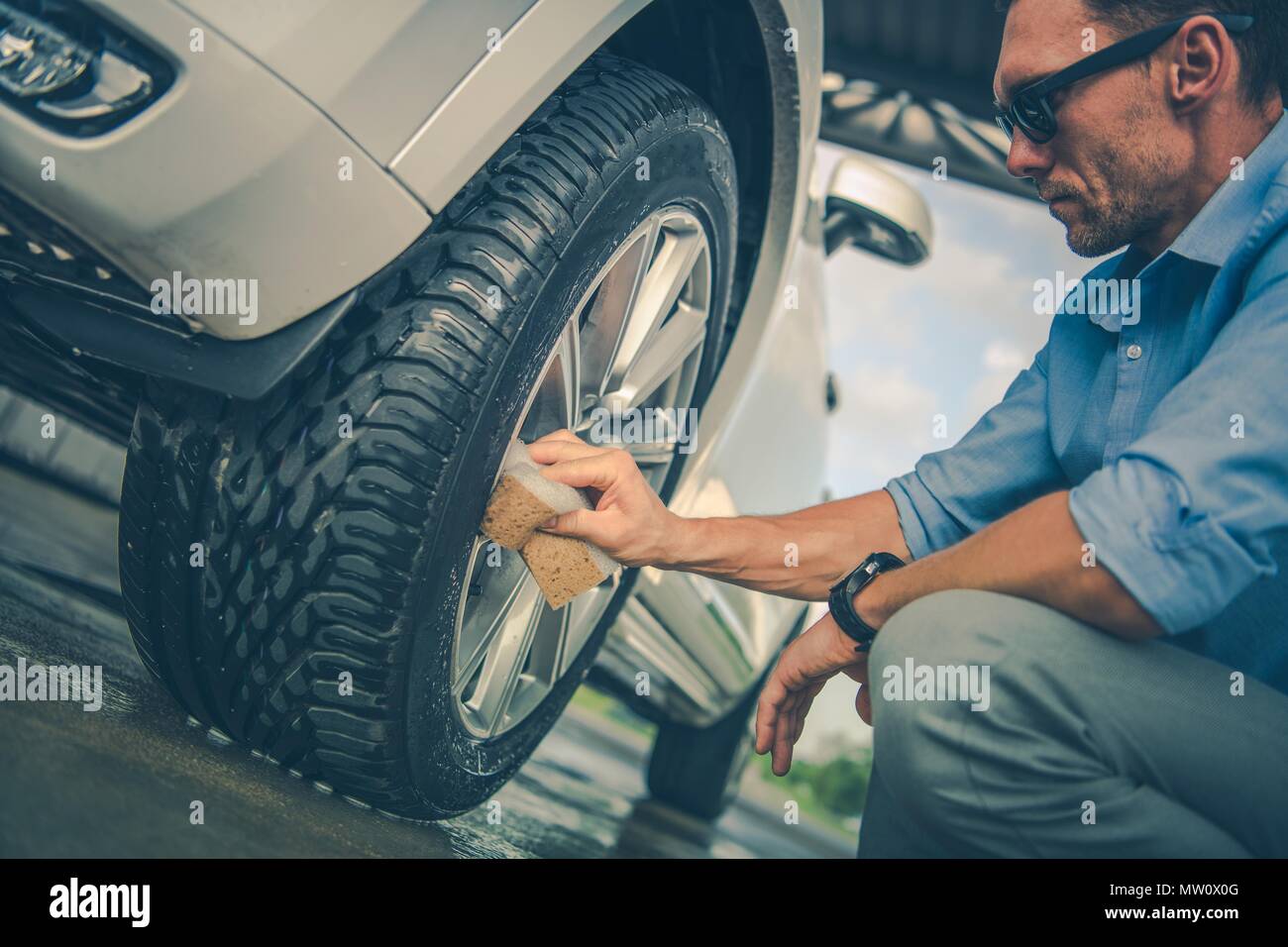 Alloy Wheels Hands Cleaning. Caucasian Men in His 30s Detailing His Vehicle in the Car Wash. Stock Photo